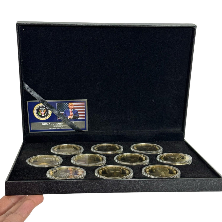 Hand holding open Trump Treasure Box with ten gold Trump coins and presidential certificate card