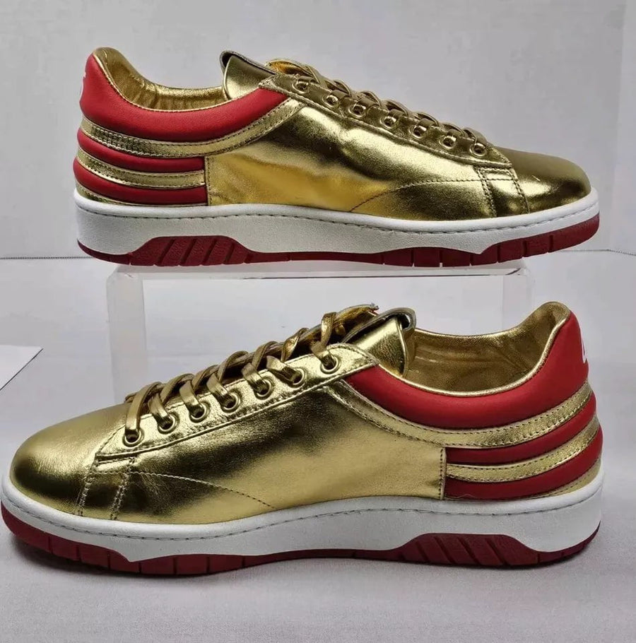 Side profile of Never Surrender gold low top sneakers with red stripes and white sole