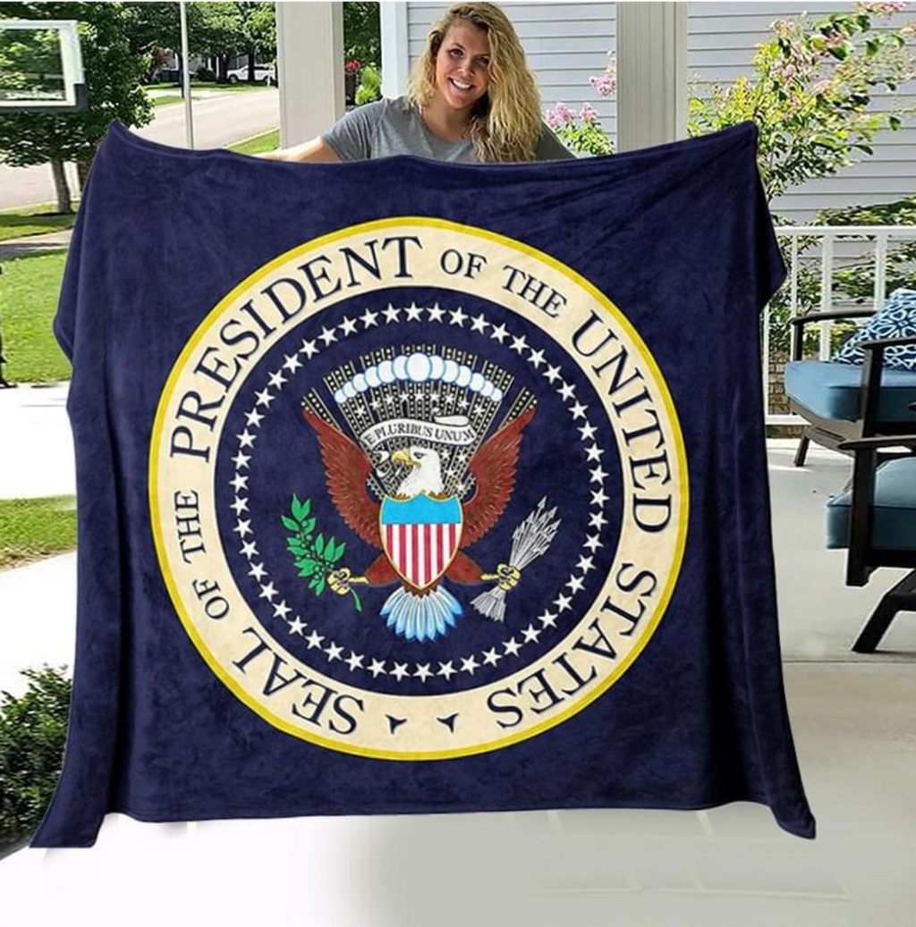 Woman holding up navy Seal of the President of the United States blanket outdoors
