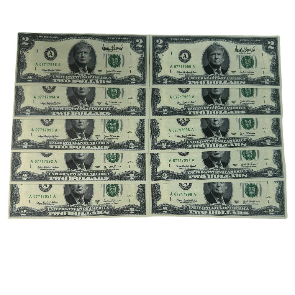 Ten Trump $2 bills laid out in rows showing serial numbers