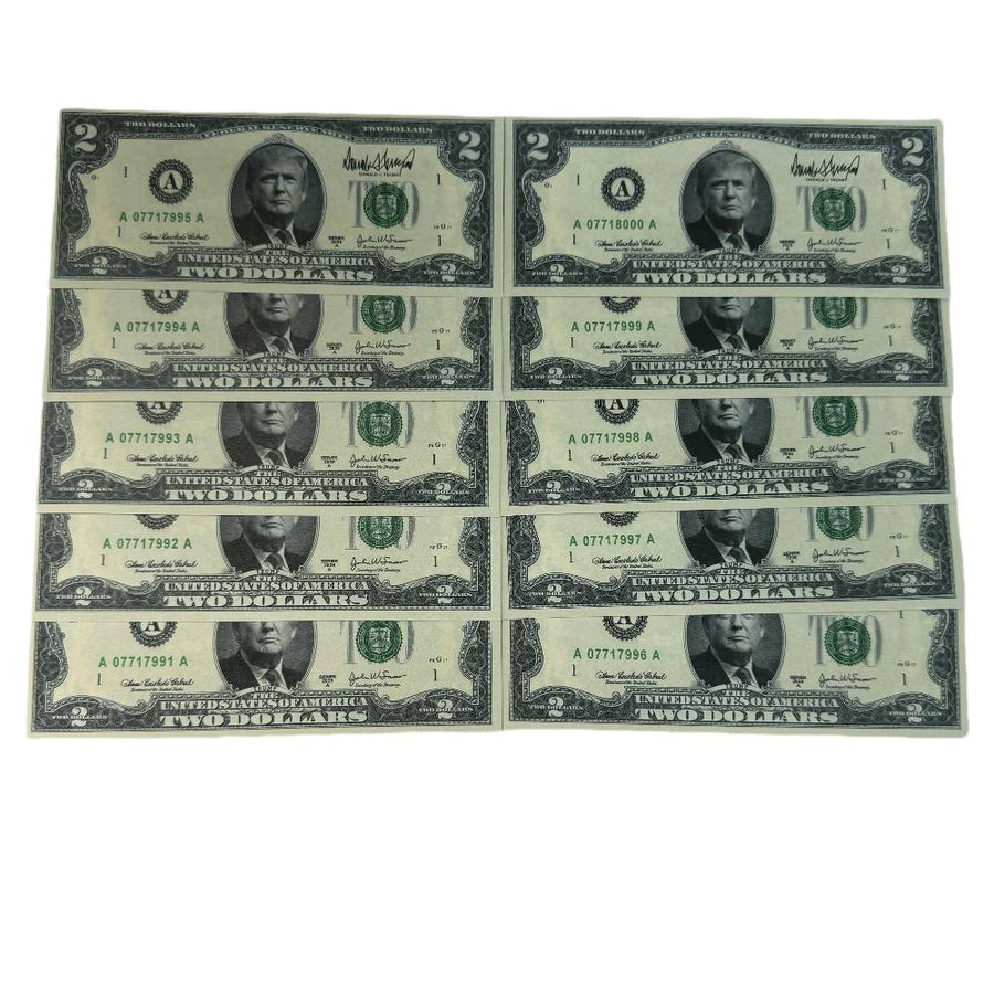 Ten Trump $2 bills laid out in rows showing serial numbers